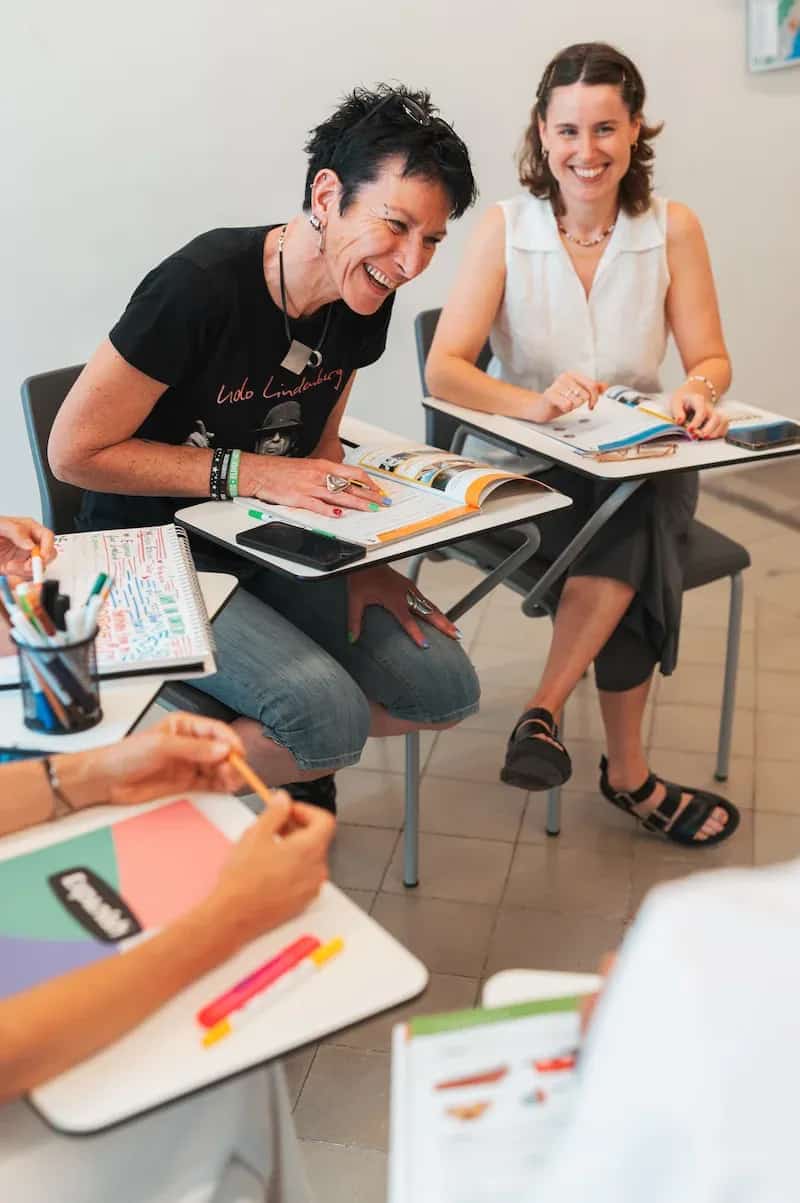 Two female students sharing a laugh during a group activity in Spanish class.