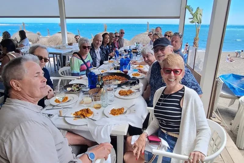 Adult language students enjoying a group lunch by the beach during a cultural activity