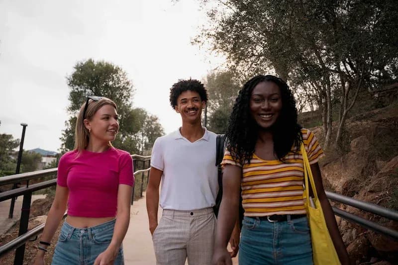 Three adult students walking outdoors in Barcelona, smiling and enjoying their time together.