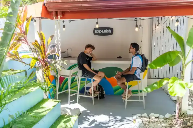 Two students chatting at the outdoor bar area of Expanish's Samara, Costa Rica campus