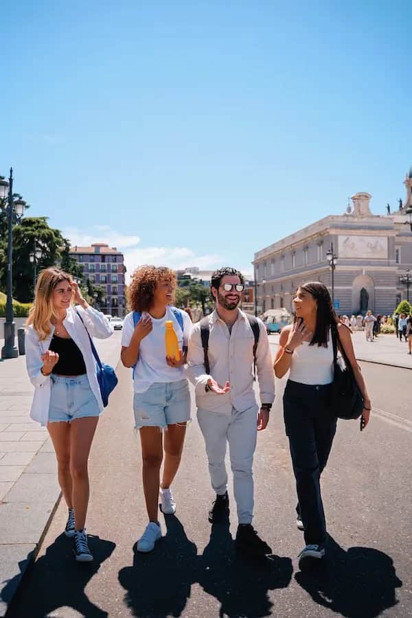 Four students walking and talking together on a sunny day in Madrid.