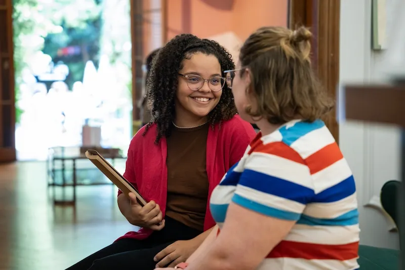 Two students talking and smiling in a lounge area at the school