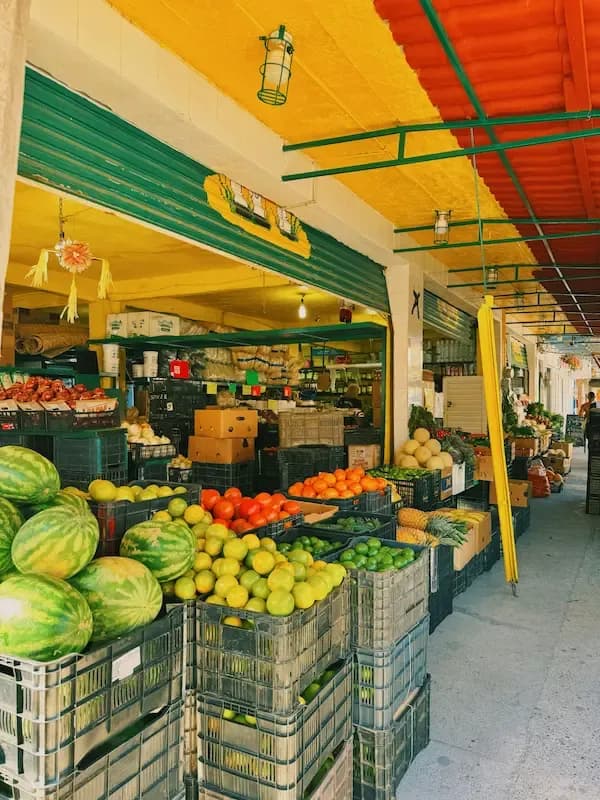 Colorful local market in Costa Rica with fresh fruits and vegetables displayed in crates.