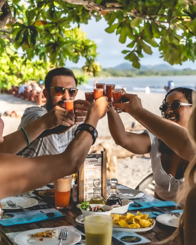 Students toasting drinks together at a beachside restaurant in Samara