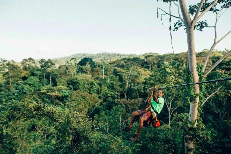 Student ziplining above a lush green forest during an adventure activity in Costa Rica.