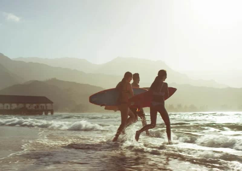 Students practicing surf stances on the beach with an instructor guiding them.