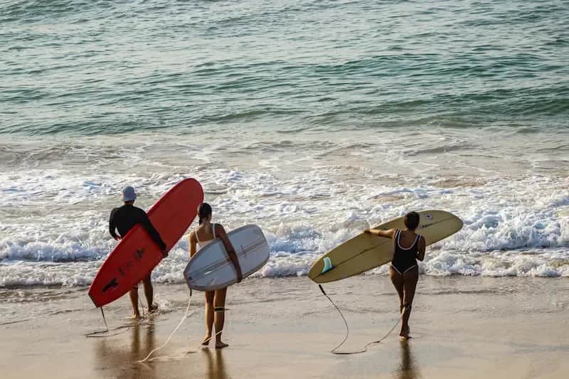 Students standing on the shore with surfboards, preparing to enter the ocean in Costa Rica.