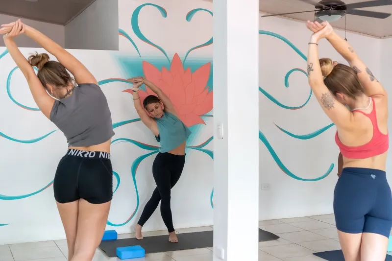 Students practicing standing yoga stretches inside a bright studio in Costa Rica.