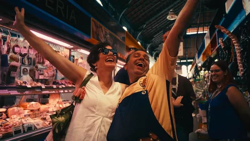Expanish 50+ student enjoying a lively moment with a vendor at a local market in Málaga.