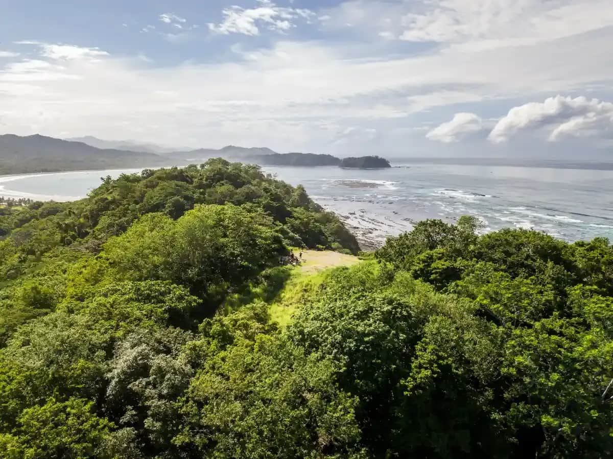 Panoramic view of a lush green coastline with ocean waves and distant islands in Costa Rica.