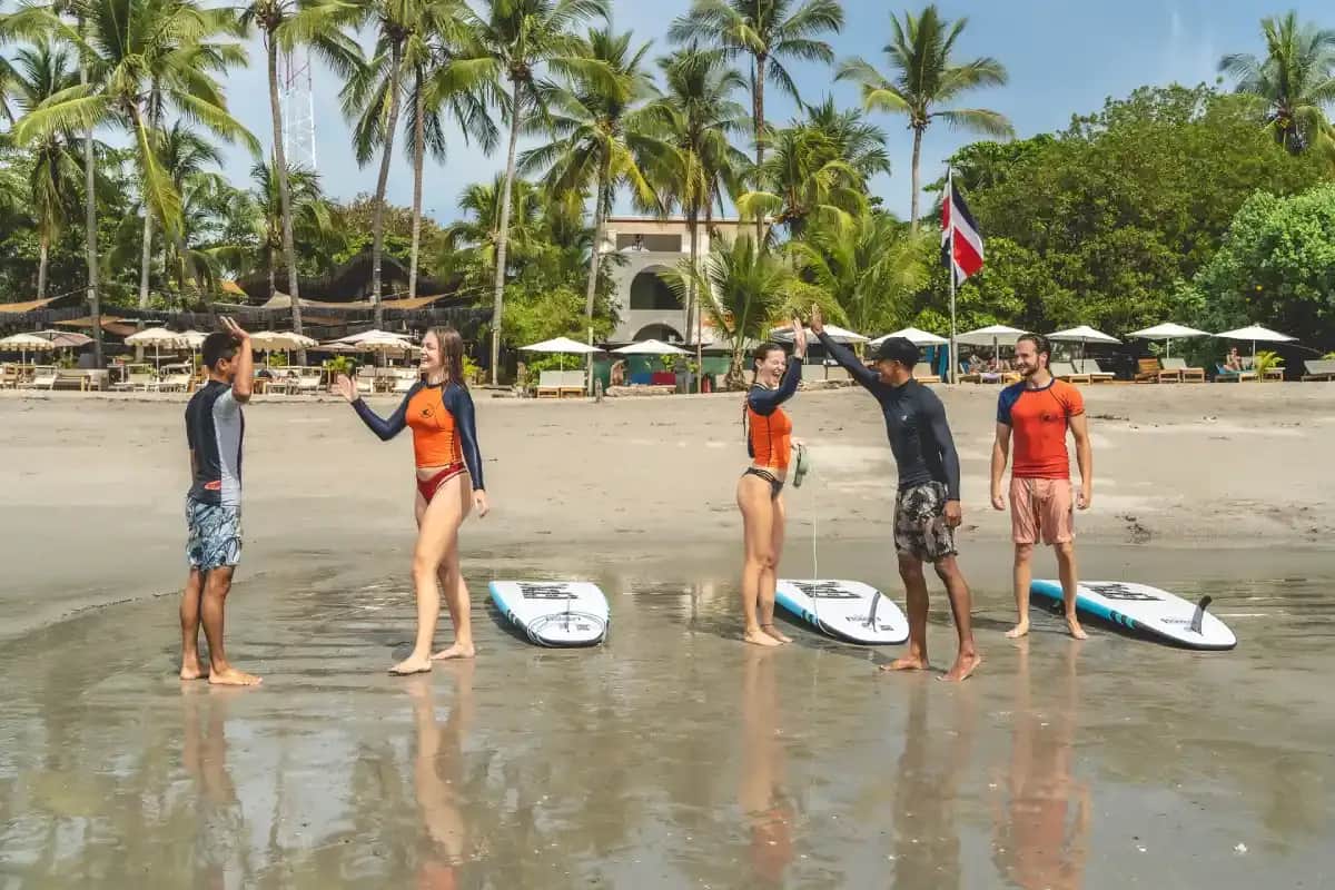 Students learning to surf on a beach in Sámara, Costa Rica, celebrating with instructors after a surf lesson.