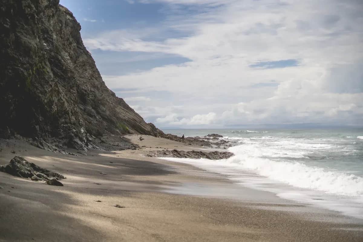 Secluded beach with rocky cliffs and gentle waves along the coast near Sámara, Costa Rica.