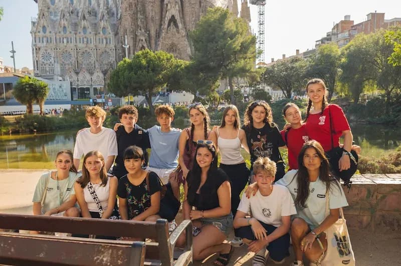 A group of Expanish summer camp students pose together during a walking tour in Barcelona, with the Sagrada Família in the background.