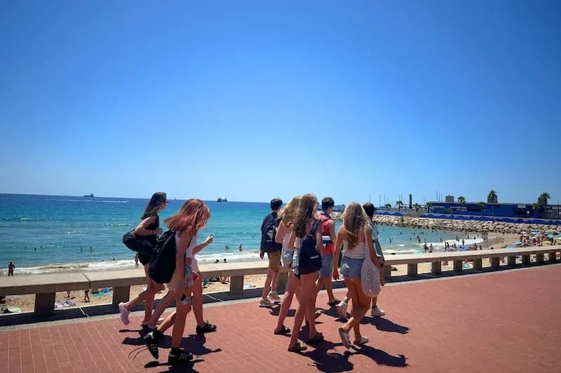 Expanish Barcelona summer camp students walking along the beachfront on a sunny day.