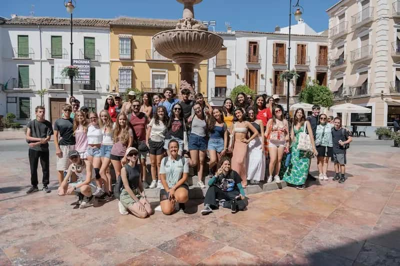 Large group of Expanish summer camp students posing together in a historic city square.