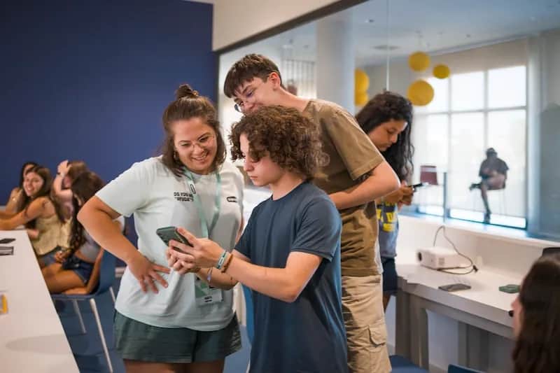 Expanish summer camp students using a smartphone during a classroom activity with staff support.