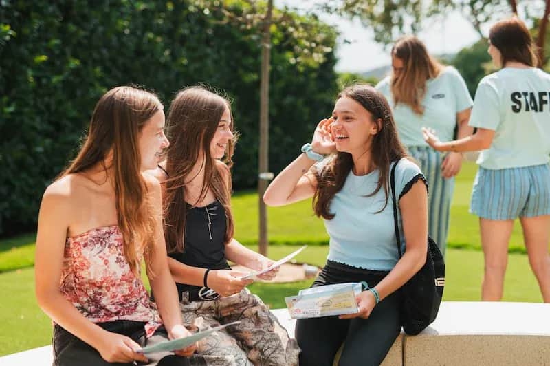 Expanish summer camp students talking and laughing together during an outdoor group activity.